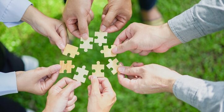 partnership, fitting together the pieces of environmental, social, and governance (ESG) strategies for sustainable success, symbolized by a jigsaw puzzle in hand. Strategic Acquisitions: Post-Integration Is The Forgotten Value Driver